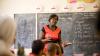 A female teacher talks to pupils in a classroom.